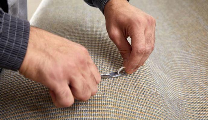 A person repairing the backing of a rug